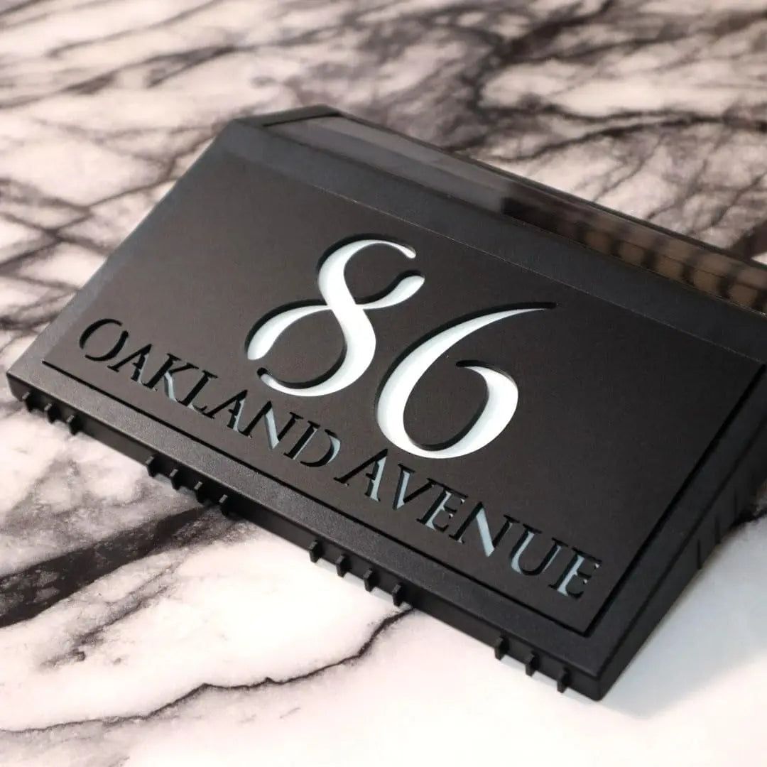 Modern black solar acrylic house sign with illuminated number 86 and Oakland Avenue address engraving.