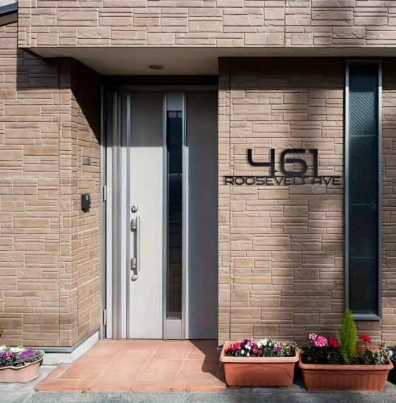 Modern house entrance with a door and address number '461 Roosevelt Ave' on a brick wall.