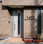 Modern house entrance with a door and address number '461 Roosevelt Ave' on a brick wall.