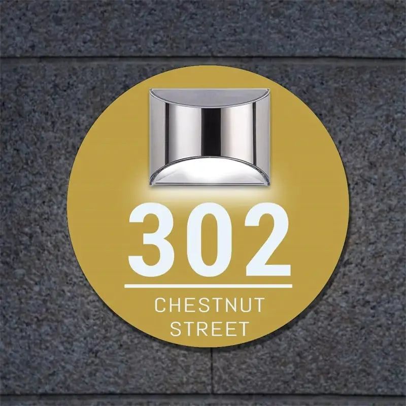 Circular solar-powered acrylic house sign with address number 302 and Chestnut Street engraved, mounted on wall.
