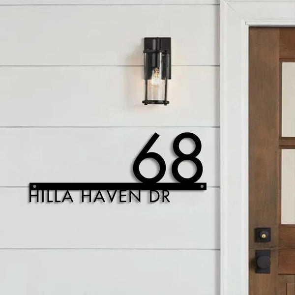 Custom modern floating house number plaque with black numbers and address on white exterior wall beside wooden door and light fixture.