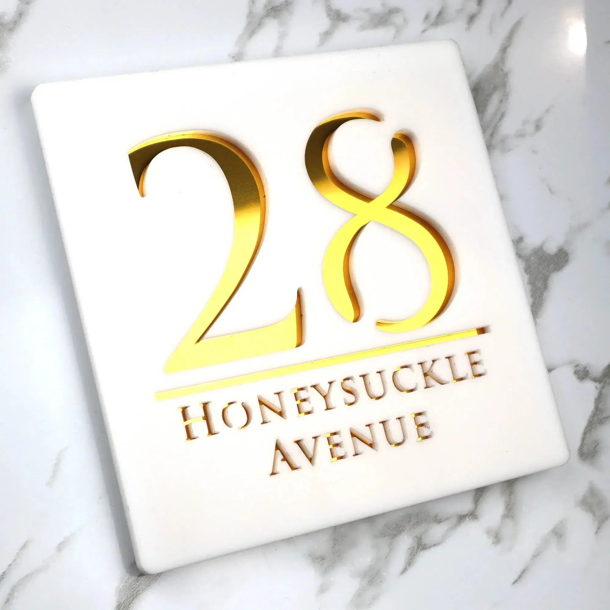 Square custom acrylic house sign with gold number 28 and Honeysuckle Avenue text on white background
