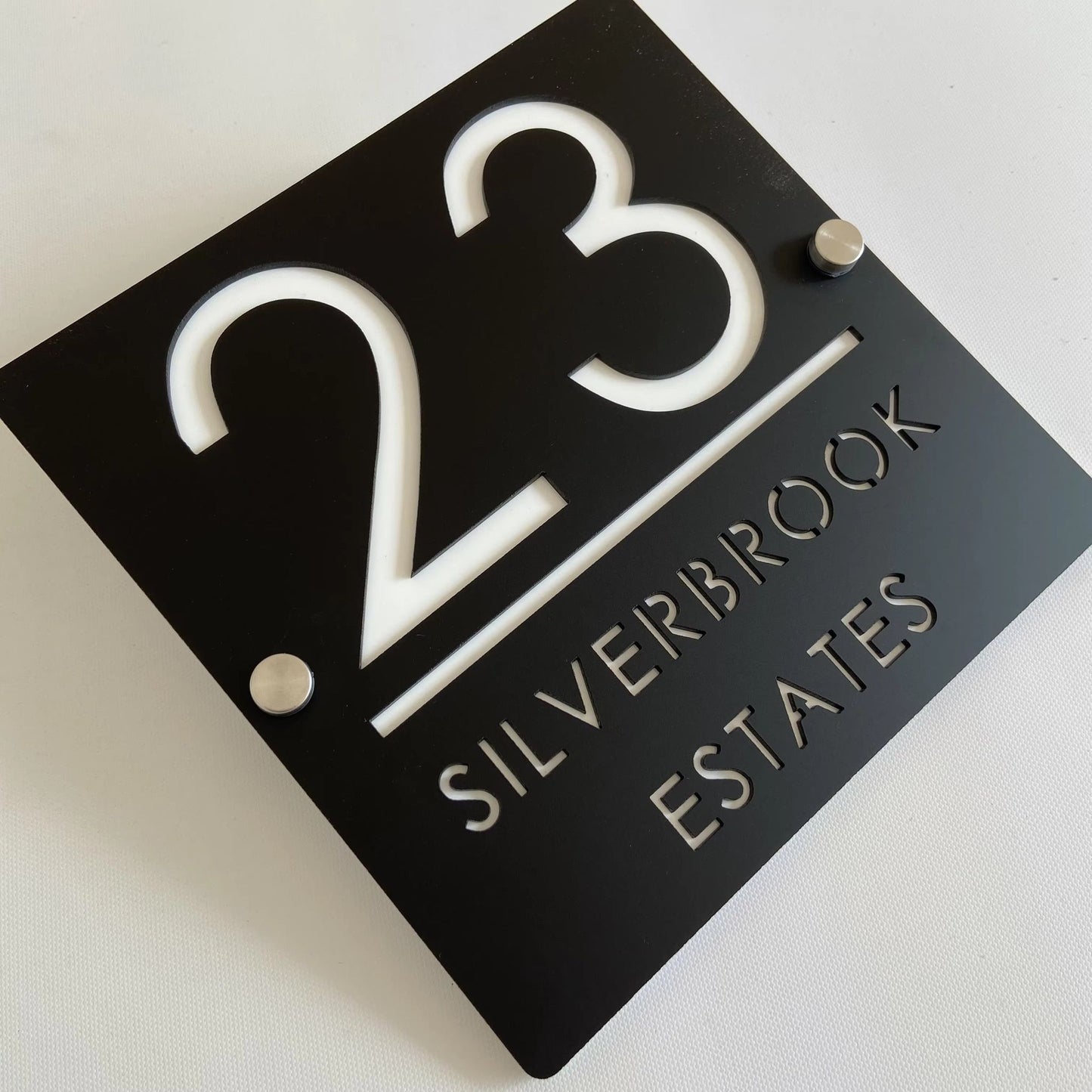 Custom black acrylic house number plaque with cut-out white lettering and standoff mounts for modern letterbox display
