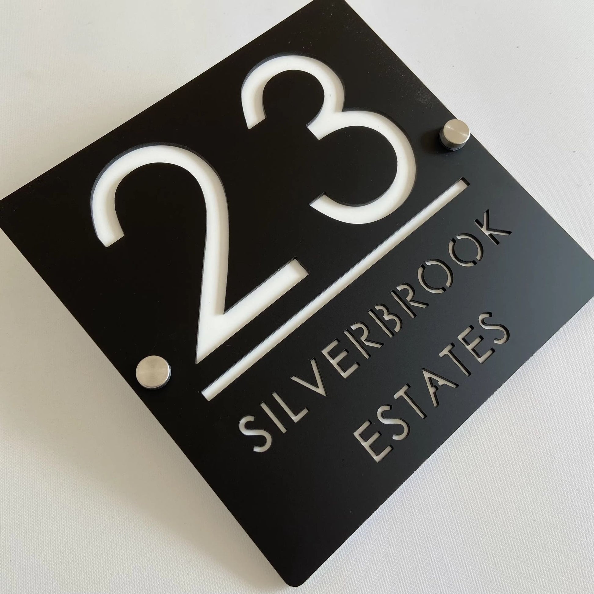 Custom black acrylic house number plaque with cut-out white lettering and standoff mounts for modern letterbox display