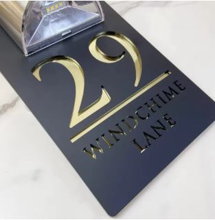 Custom solar acrylic house sign with engraved gold numbers and letters, designed for weather resistance and outdoor mounting.