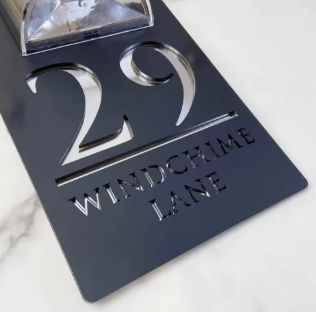 Custom black acrylic house sign with solar light, displaying number 29 and Windchime Lane address.