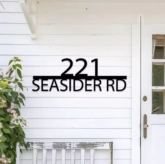 House number sign '221 SEASIDER RD' on a white door with decorative elements.