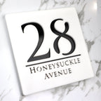 Square custom acrylic house sign displaying number 28 and Honeysuckle Avenue in black text on white background