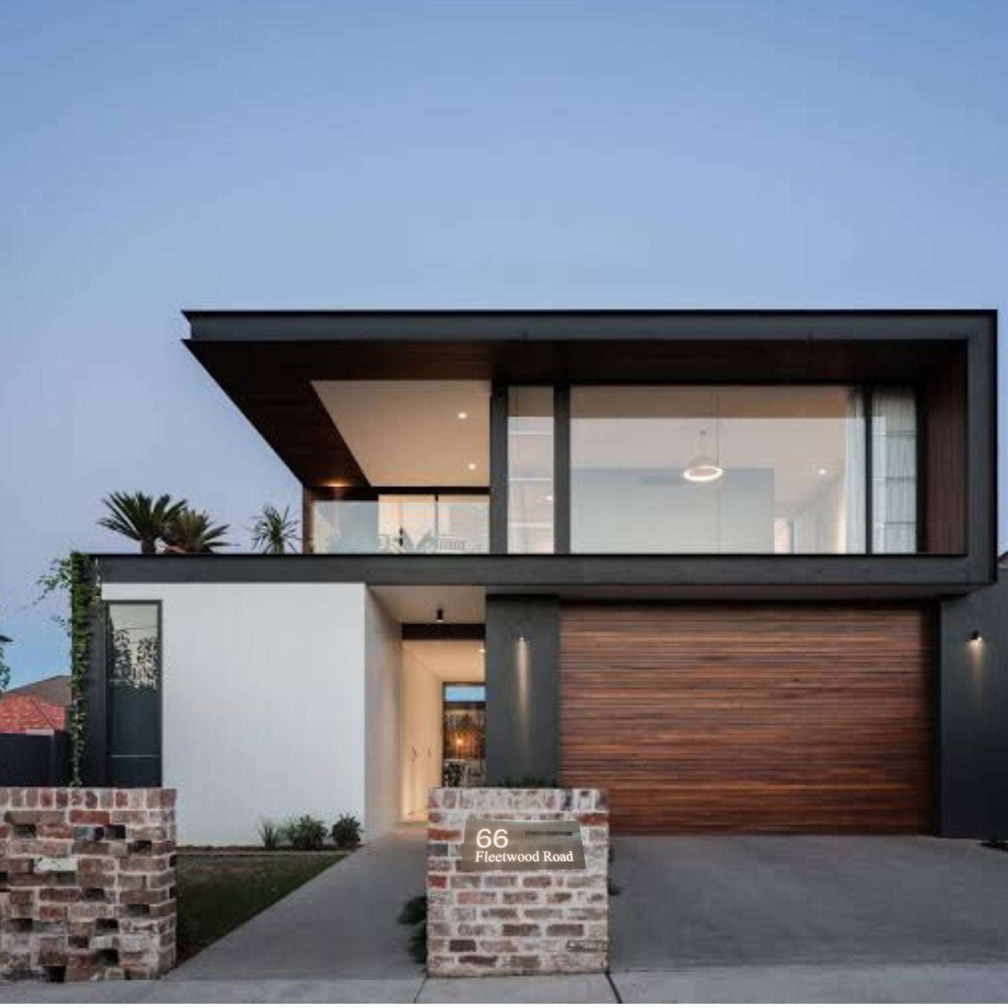 Modern home exterior with stainless steel LED mailbox slot letterbox illuminated at dusk, displaying house number and street name.