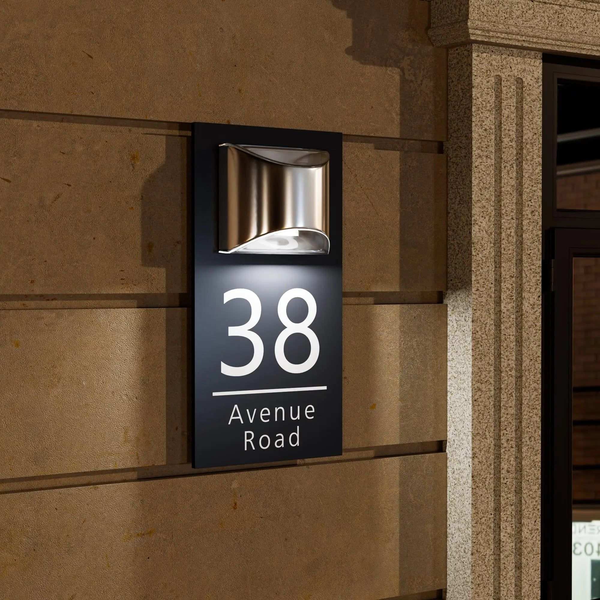 Rectangular custom acrylic house number sign with modern light fixture mounted on exterior wall at night
