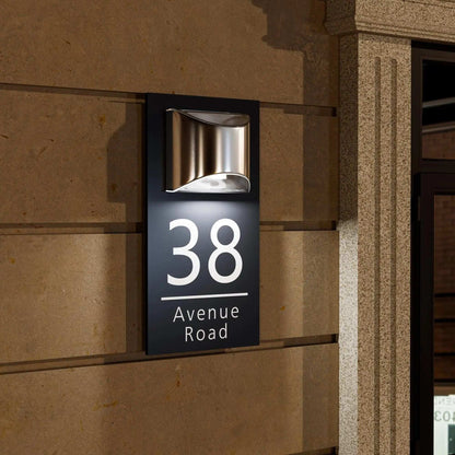 Rectangular custom acrylic house number sign with modern light fixture mounted on exterior wall at night