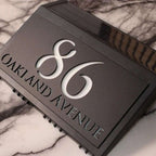 Modern solar-powered custom acrylic house sign with laser-etched address numbers and text on black panel