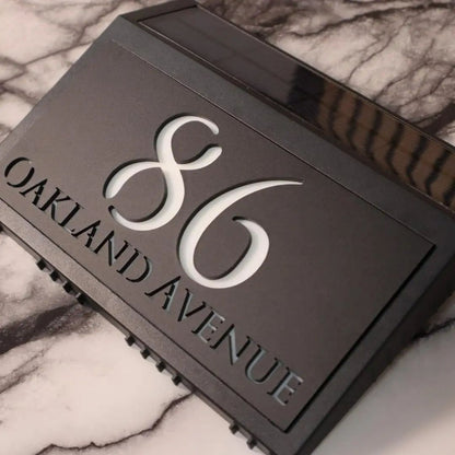 Modern solar-powered custom acrylic house sign with laser-etched address numbers and text on black panel