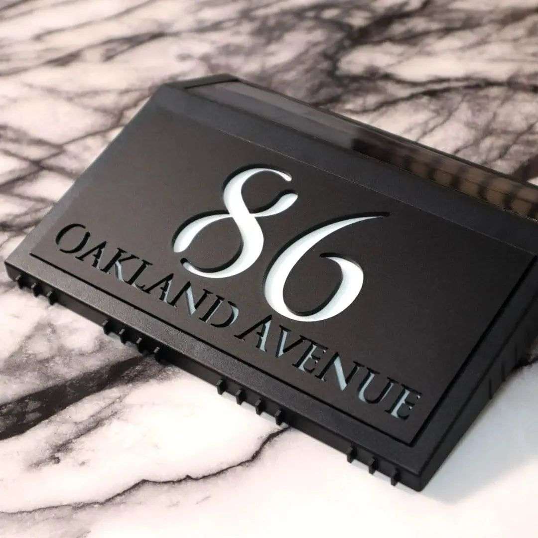 Modern black solar-powered acrylic house number sign with backlit white engraving for 86 Oakland Avenue.